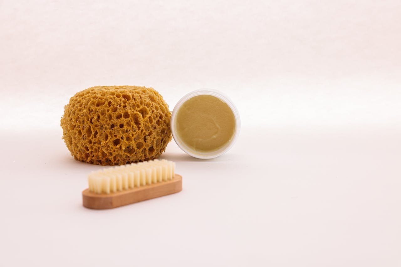 A natural sponge, brush, and skincare cream arranged for a minimalist spa setting.